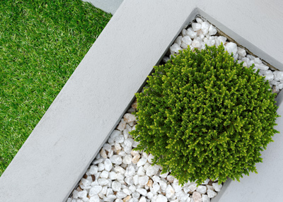 modern landscape design featuring green bush, grey concrete borders, and white gravel enhancing three dimensional appeal